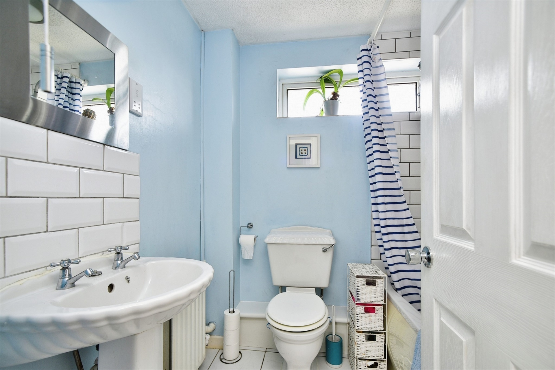 Bathroom with sky blue walls and white tiles.